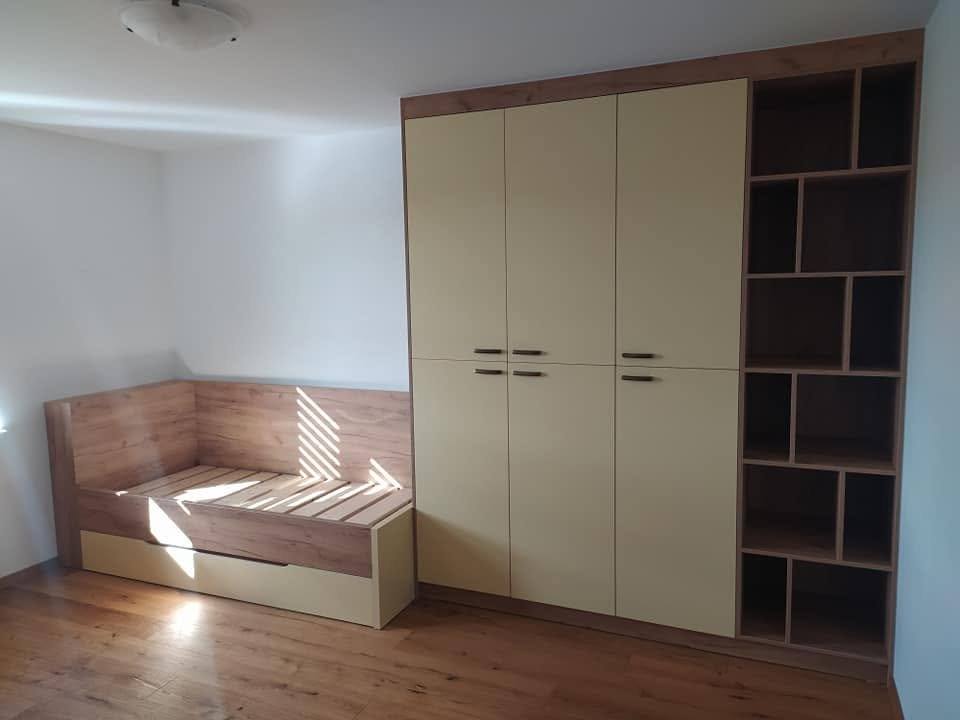 Kinderzimmer mit Bett, cremefarbenem Kasten und Regal