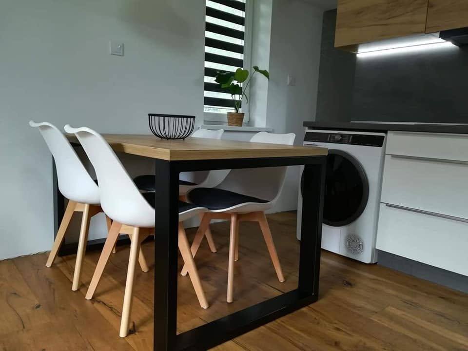 Esstisch mit schwarzem Gestell und weißen Sesseln bei der Küche