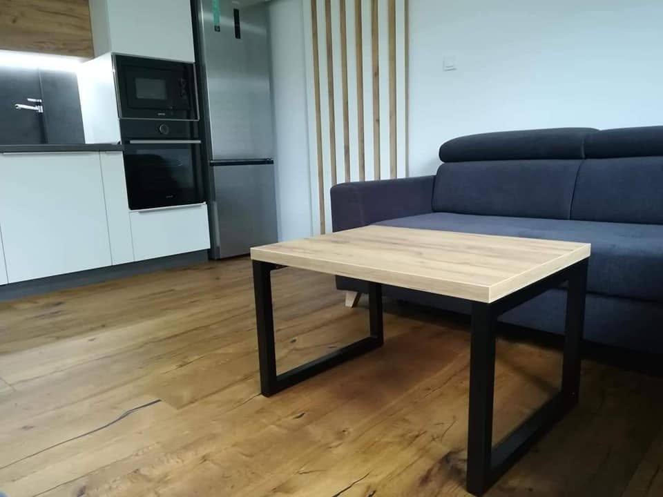 Couchtisch mit Platte in Eichenoptik vor dem dunkelblauen Sofa