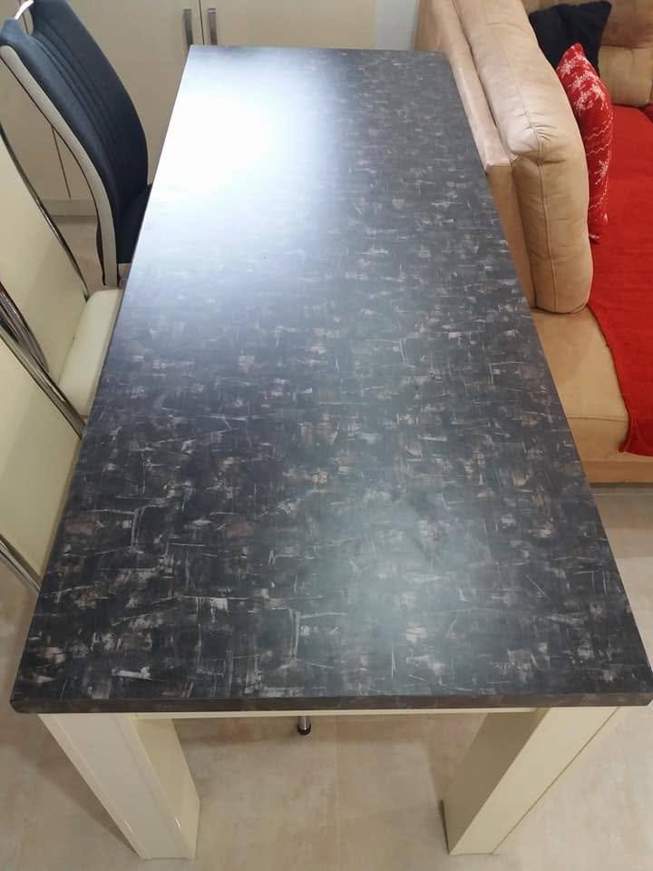 Esstisch mit dunkler Granitplatte und cremefarbenen Beinen
