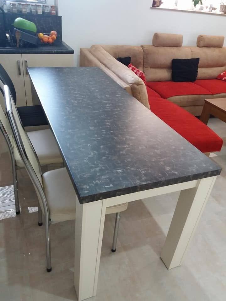 Tisch mit Granitplatte und cremefarbenen Beinen neben dem roten Sofa