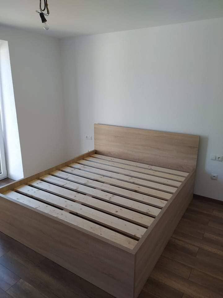 Schlichtes Bett in Eichenoptik im hellen Zimmer