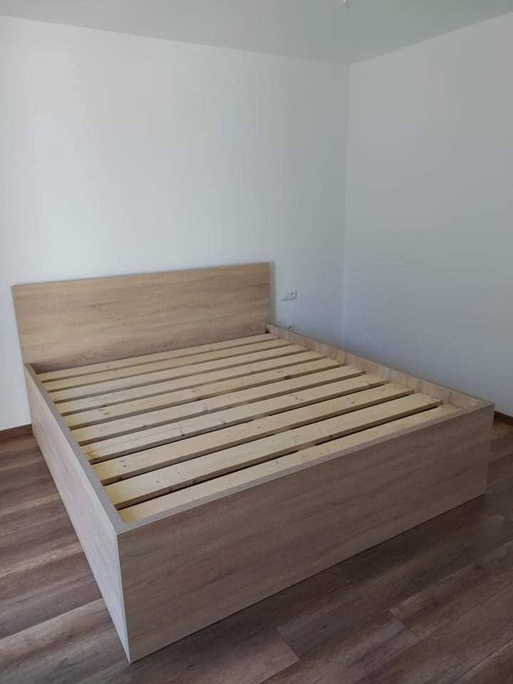 Bett in Eichenoptik mit Lattenrost auf dunklem Boden