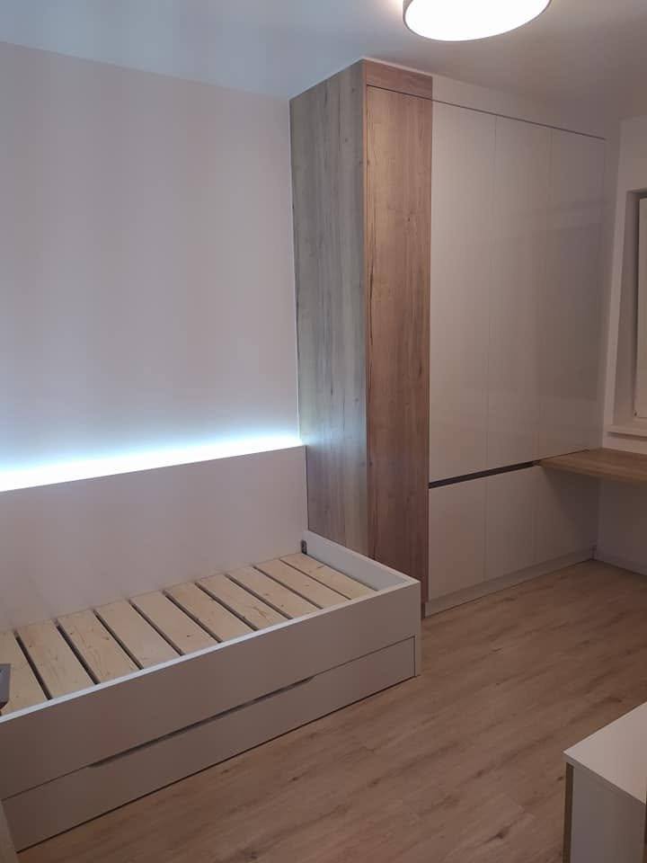 Zimmer mit Bett auf Lattenrost, beleuchteter Verkleidung und hohem Kasten