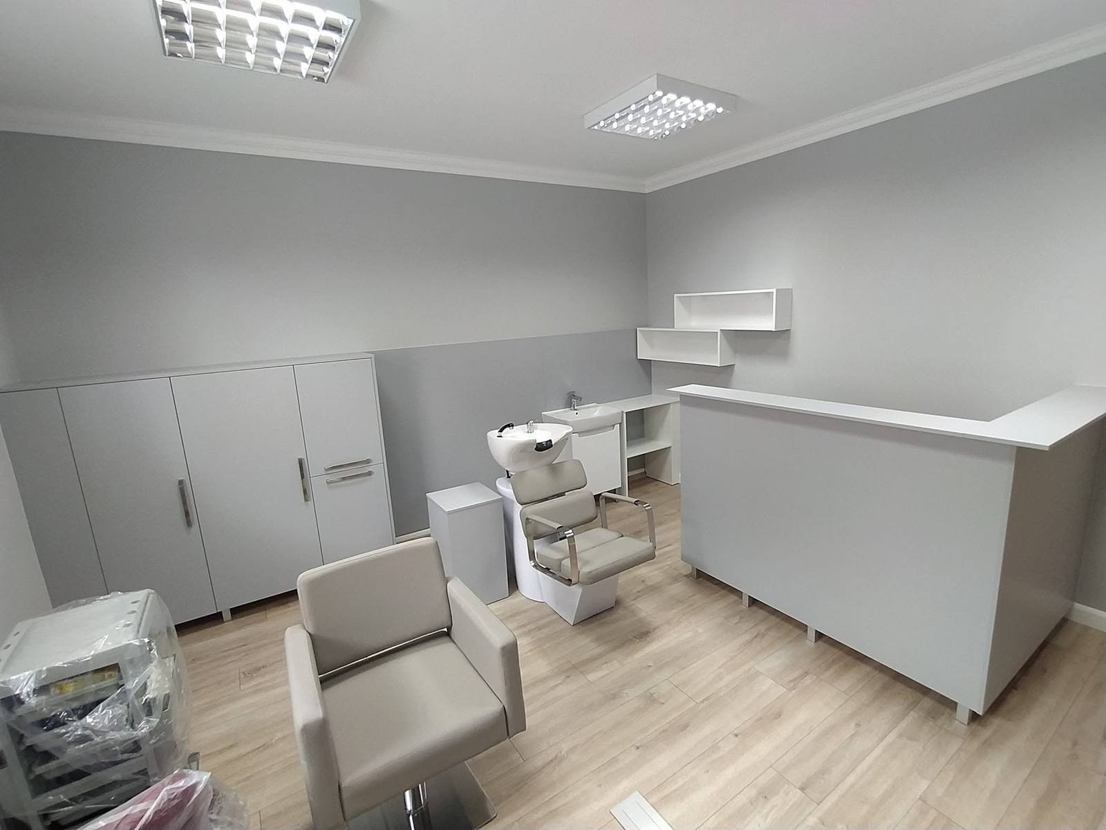 Friseursalon mit hellgrauem Tresen, Schränken und Regalen