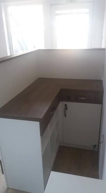 Ecktheke mit dunkler Platte und weißen Schränken im Salon