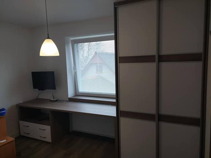 Arbeitszimmer mit Schreibtisch unter dem Fenster und Schwebetürenkasten