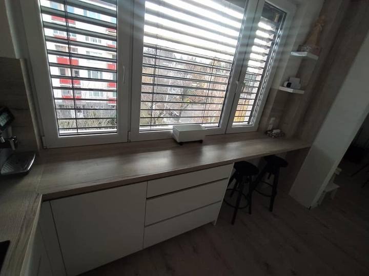 Lange Arbeitsplatte unter dem Fenster mit Laden und Schränken
