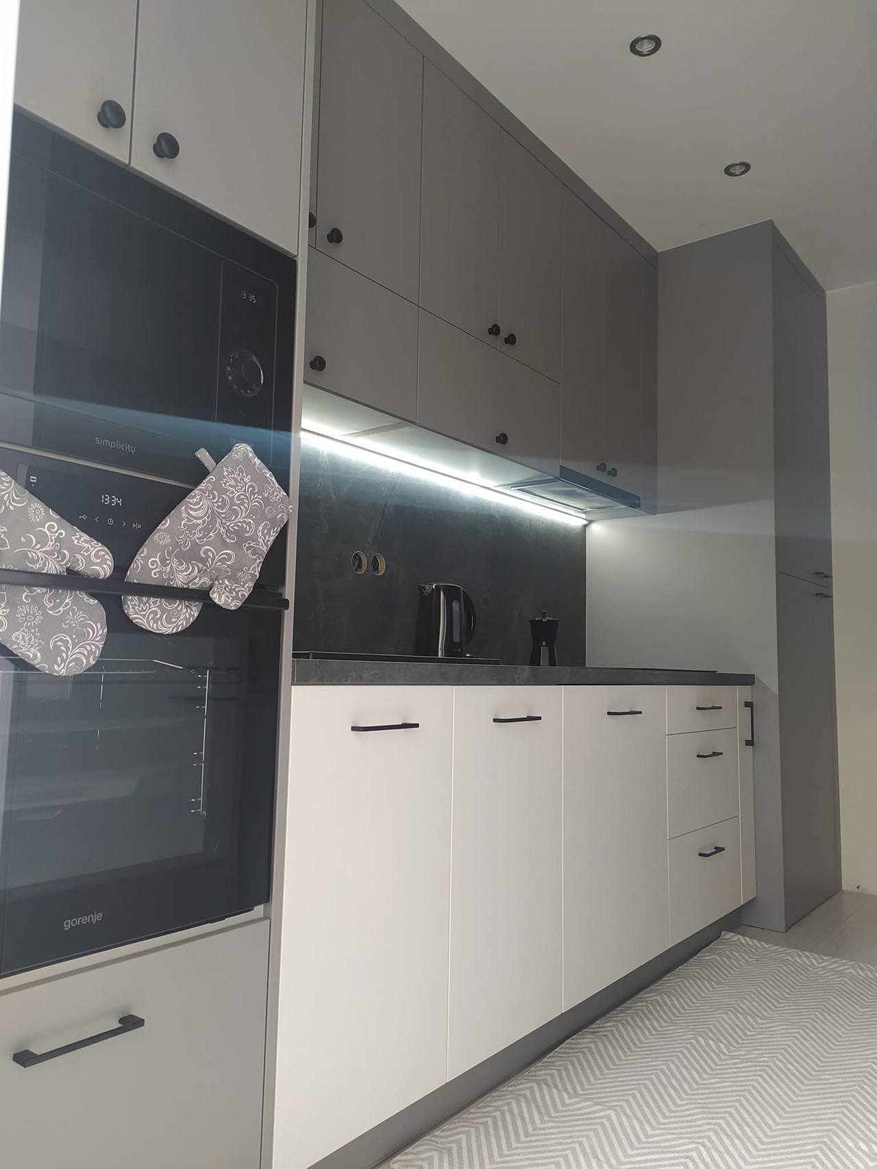 Küche in Kaschmirton und Grau mit LED-Beleuchtung und Hochschrank.