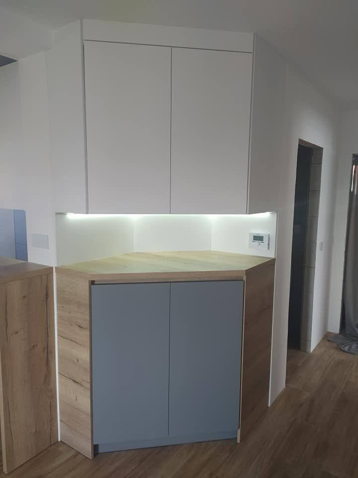 Grauer matter Schrank im Eichenrahmen unter dem weißen Hängekasten.