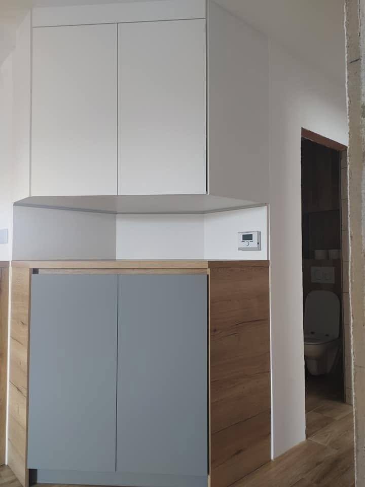 Detail der Küchennische mit grauem Schrank und Wandsteckdose.