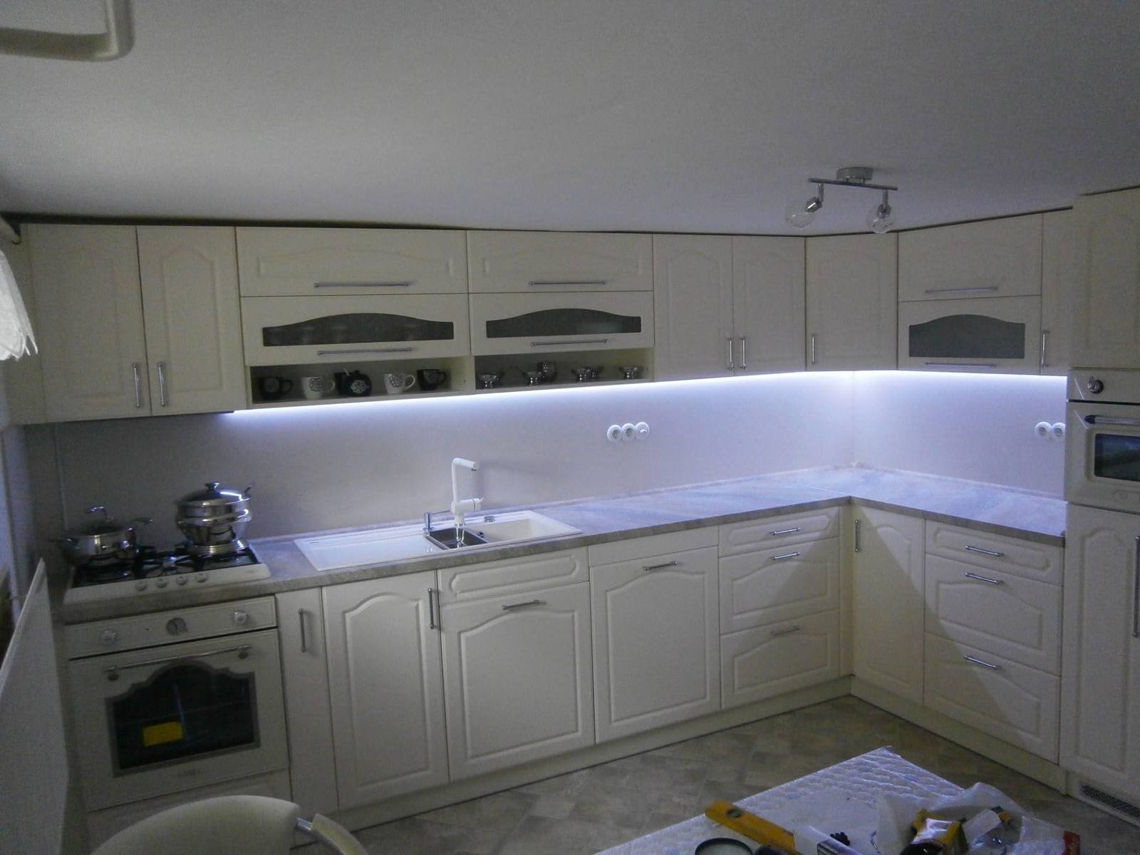 Cremefarbene L-Küche mit LED-Licht und Backrohr unter dem Kochfeld