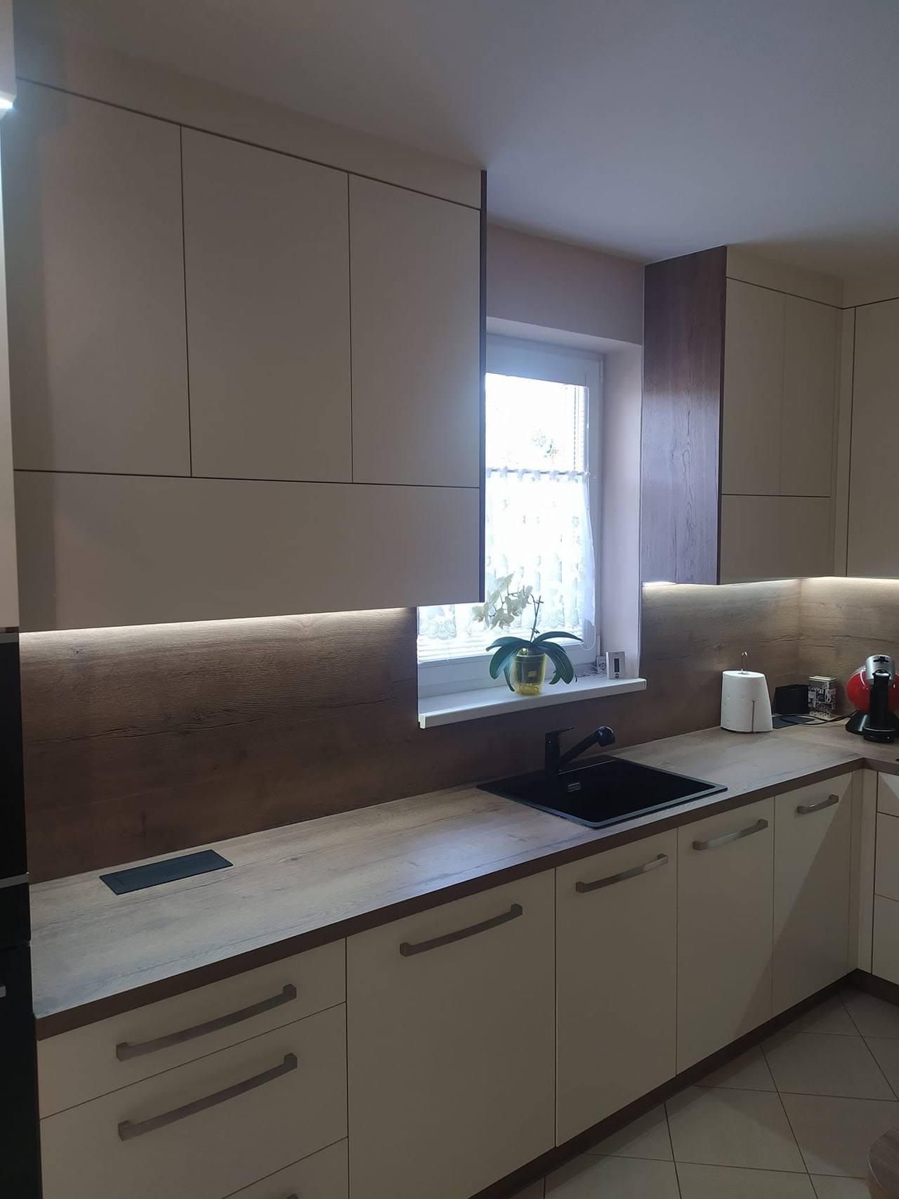 Zeile beim Fenster mit dunkler Rückwand und Hochschrank mit Backrohr