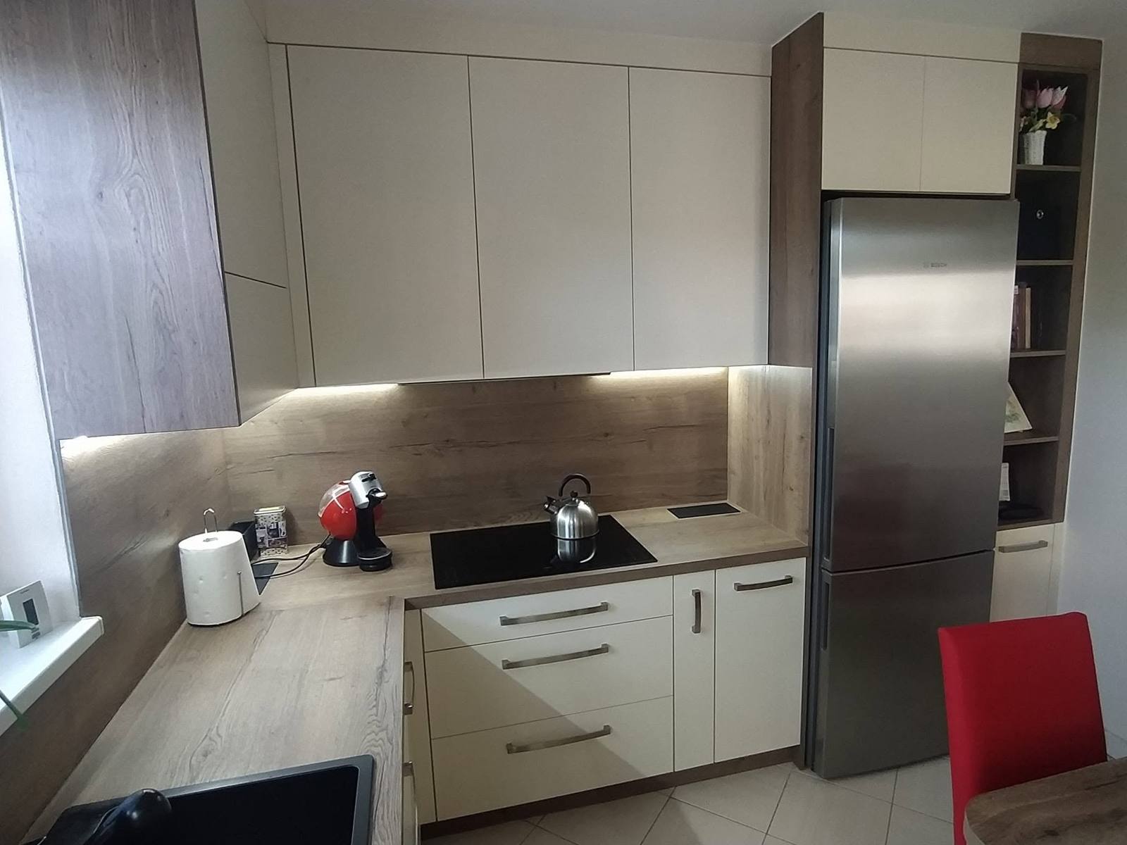 Edelstahl-Kühlschrank in der Nische neben einem schmalen Regal