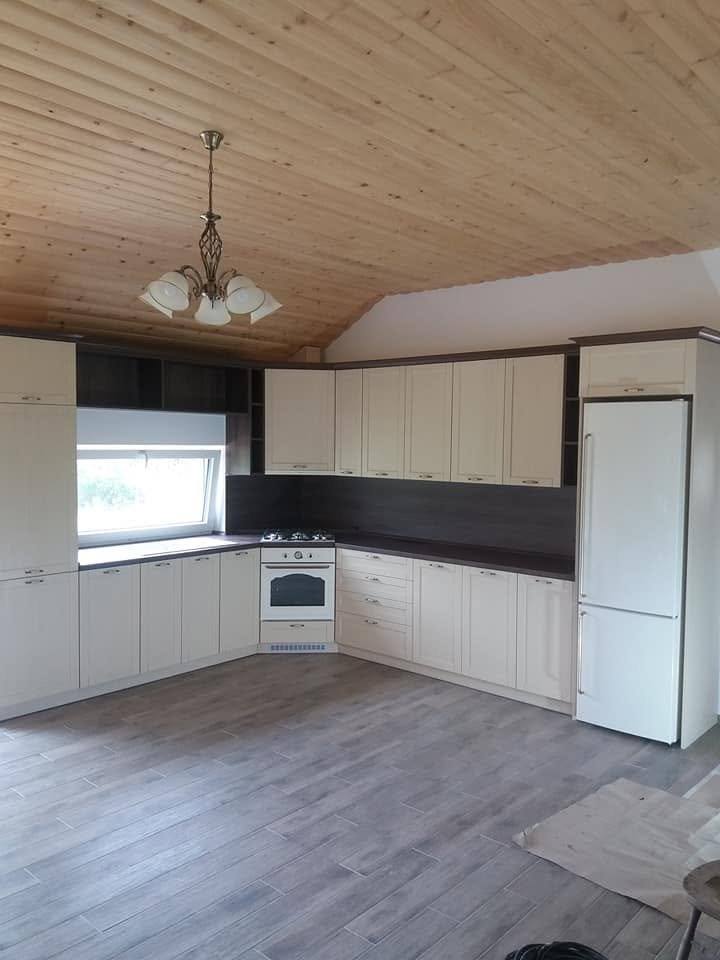 Cremefarbene Küche mit dunkler Rückwand und Hochkasten mit Kühlschrank