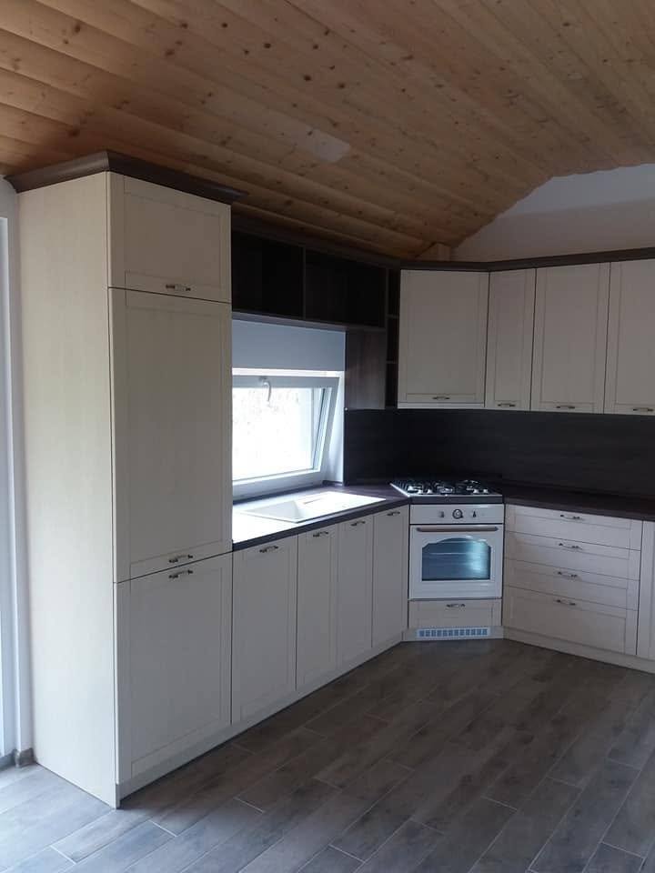 Cremefarbene L-Küche mit Retro-Backrohr unter der Holzdecke