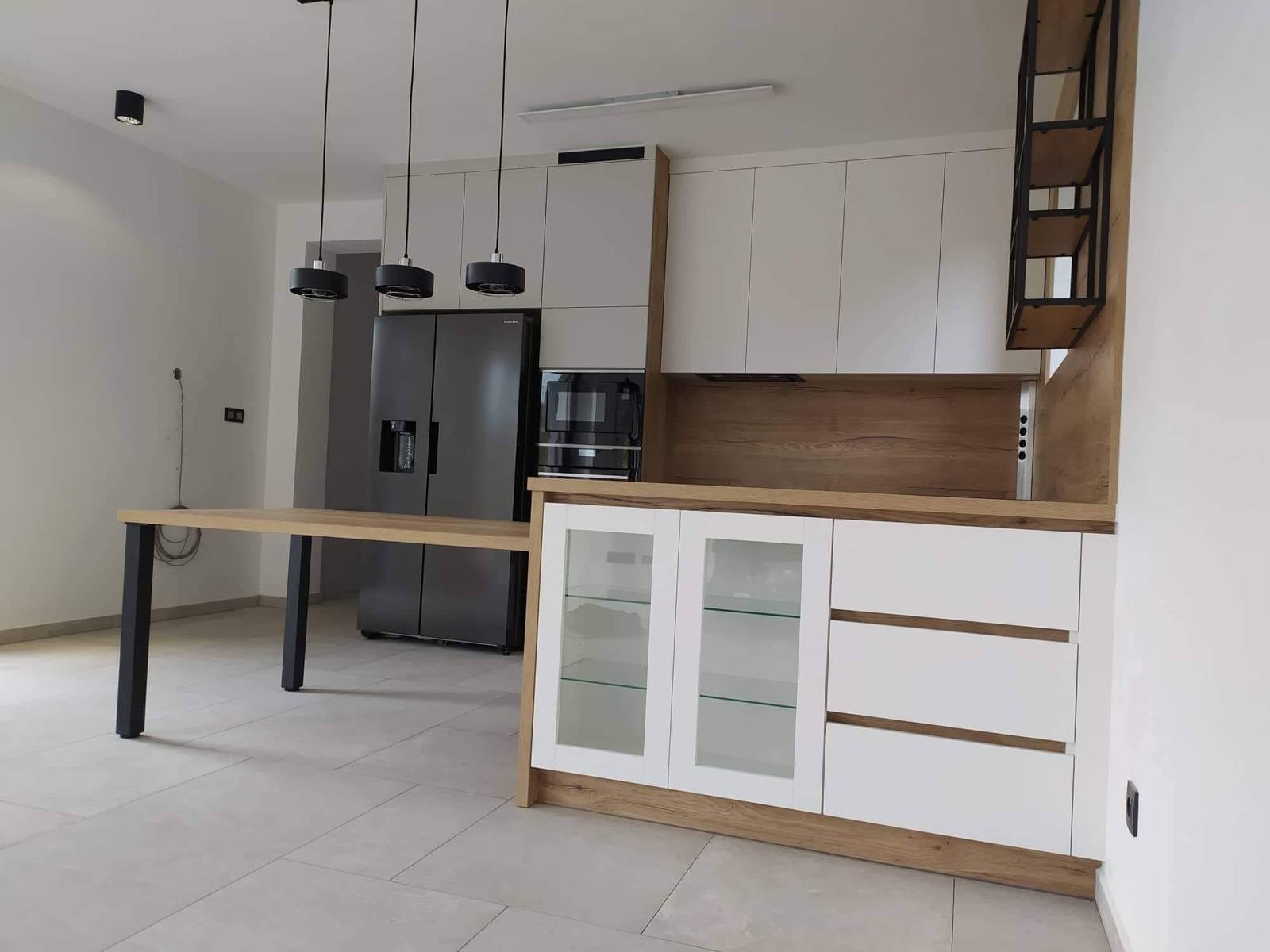 Halbinsel mit Glasvitrine und Tisch vor schwarzem Kühlschrank