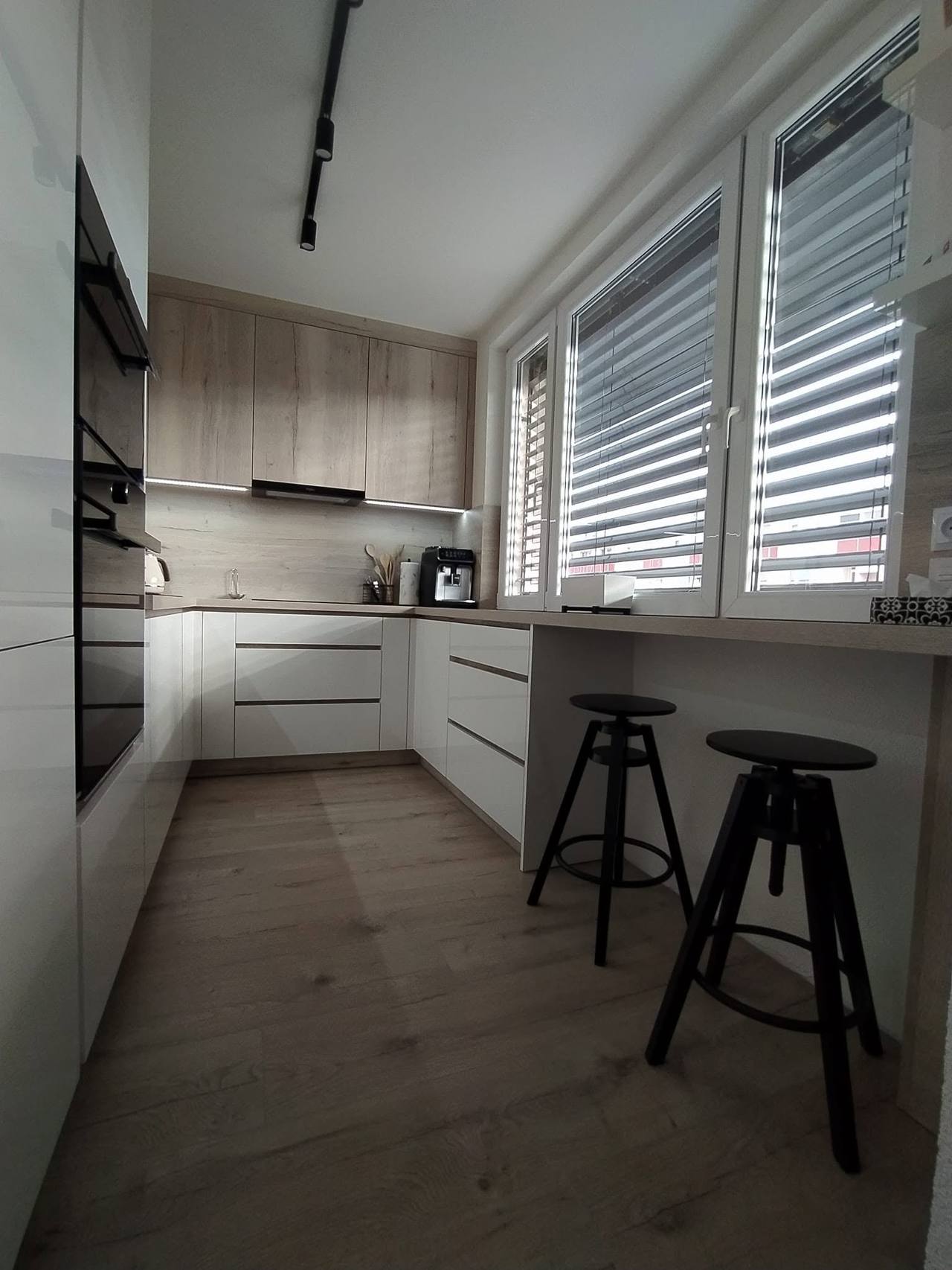 Blick auf die Küche mit Bartheke unter den Fenstern und Hockern
