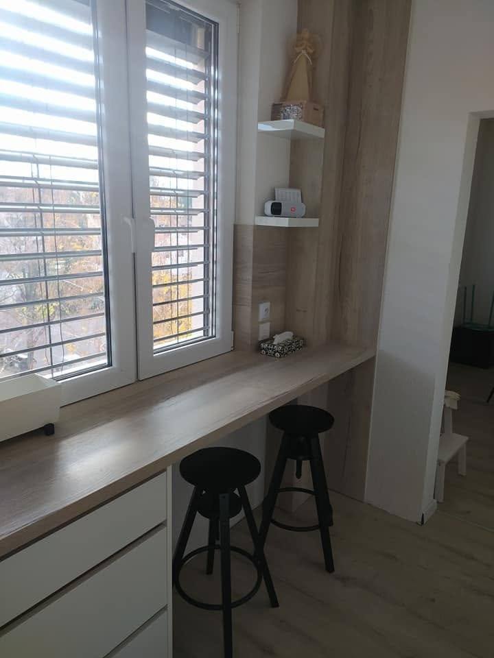 Bartheke am Fenster mit weißen Laden und schwarzen Hockern