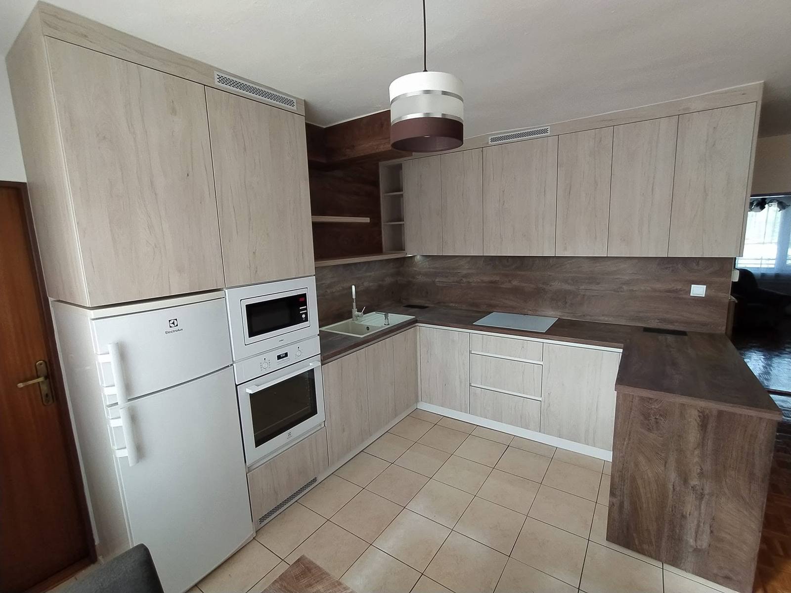 Hochschrank mit weißer Mikrowelle und Backrohr neben dem Kühlschrank
