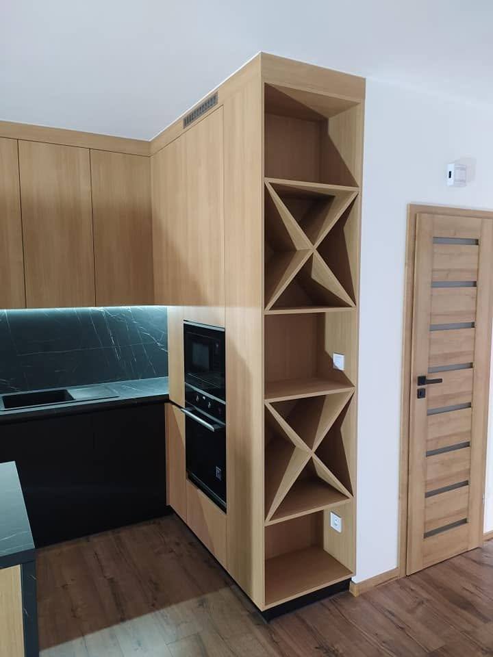 Weinregal und Backrohre in der Eichenwand neben der Tür