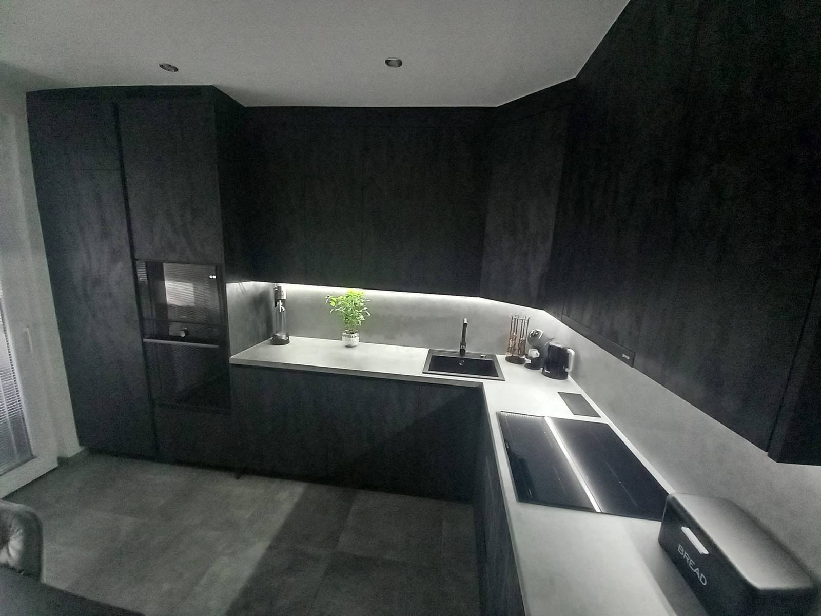 Geräumige dunkle Küche mit Hochschrank und heller Arbeitsplatte.