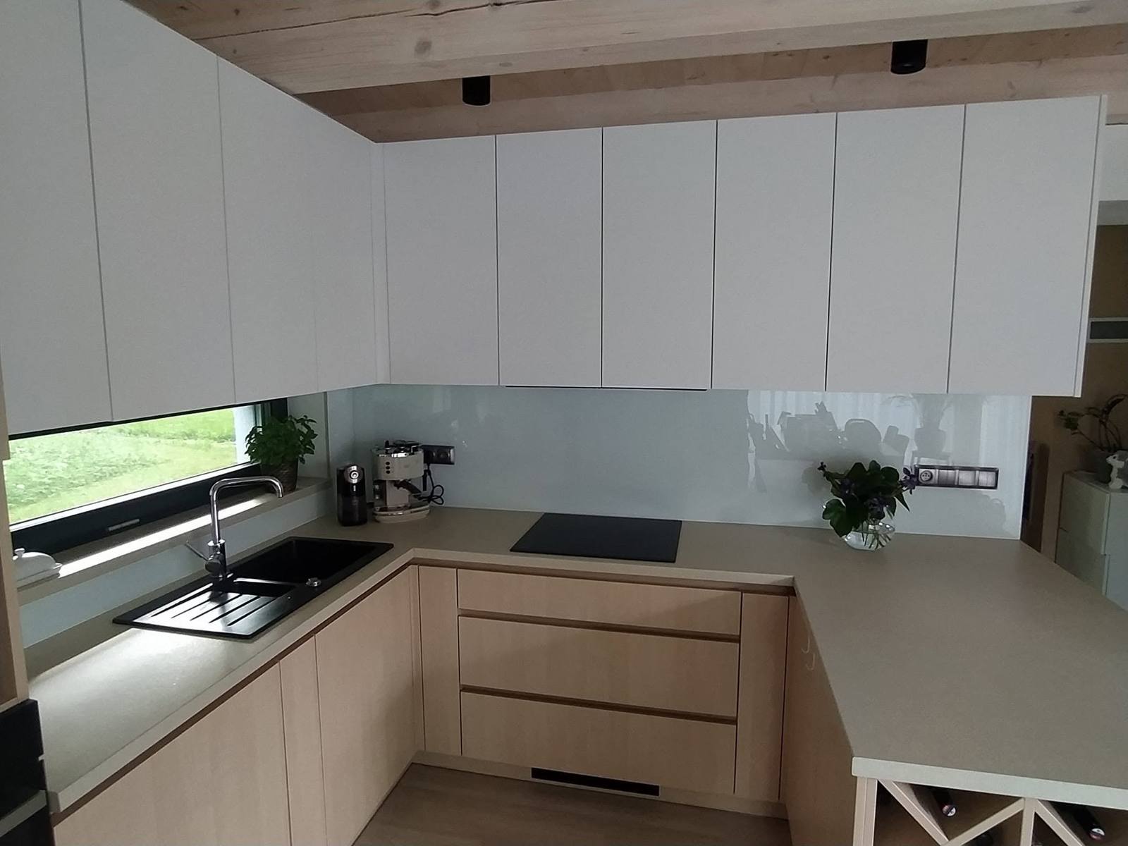 U-Küche mit Glasrückwand und Fensterband über der Spüle