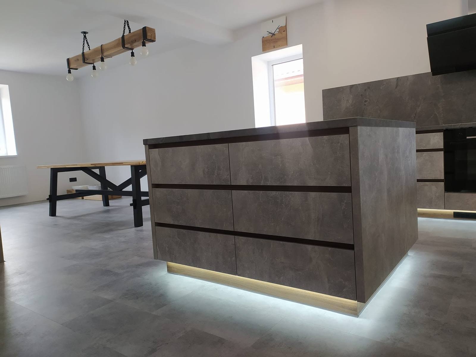 Kücheninsel in Betonoptik mit Esstisch im Hintergrund