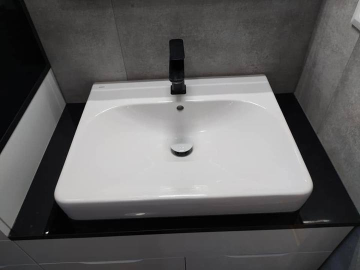 Weißes Waschbecken mit schwarzer Armatur auf schwarzer Platte
