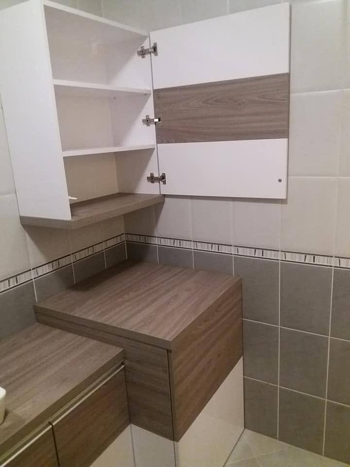 Bad mit offenem weißem Schrank und Wannenverkleidung dahinter