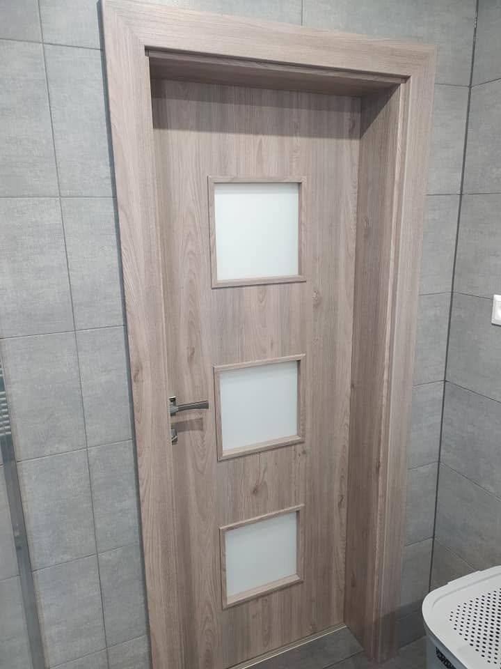 Badezimmertür in Eichendekor mit drei quadratischen Milchglasfeldern.