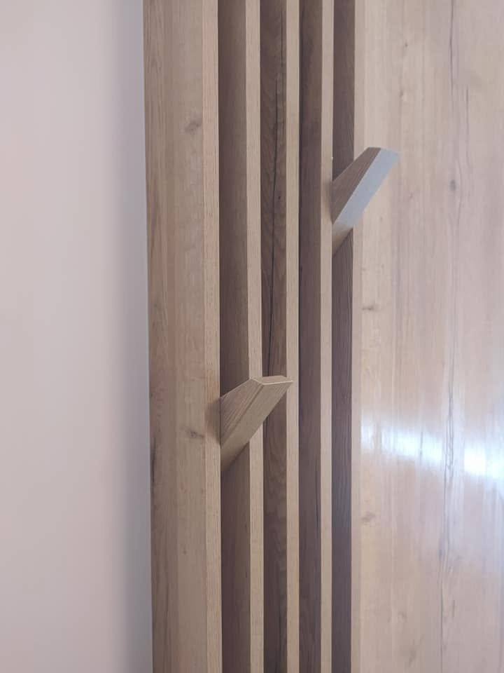 Detail dreveného háčika medzi lamelami s tmavými medzerami