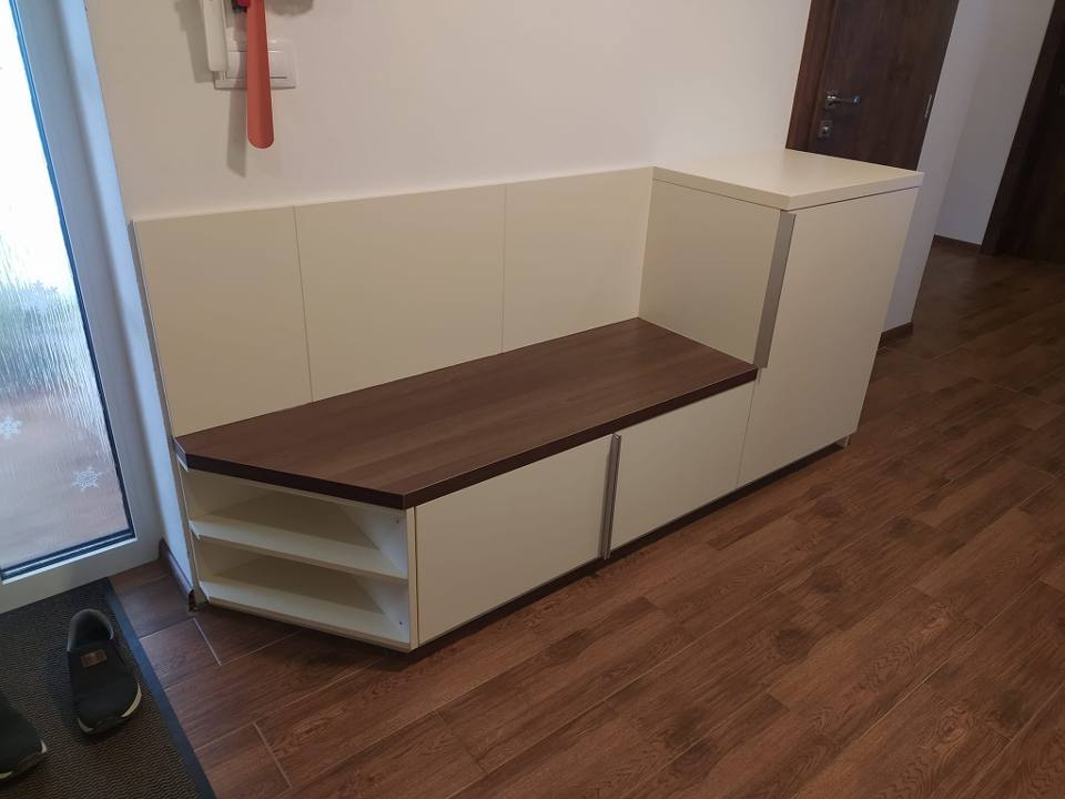 Cremefarbene Sitzbank mit dunkler Nussbaum-Sitzfläche und offenen Schuhregalen.