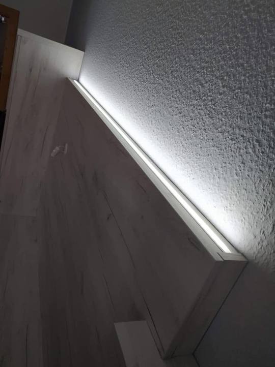 Lichtleiste unter dunklem Oberkasten beleuchtet die strukturierte Wand