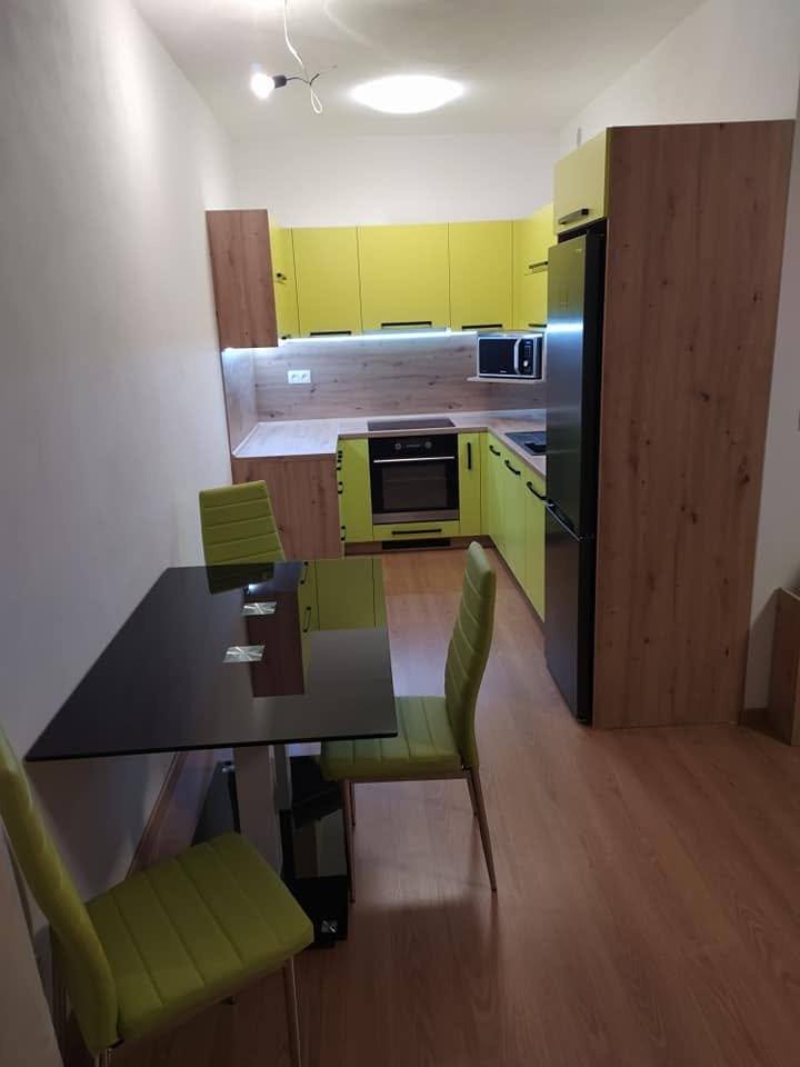 Grüne Küche mit hohem Eichenschrank und Esstisch am Fenster.