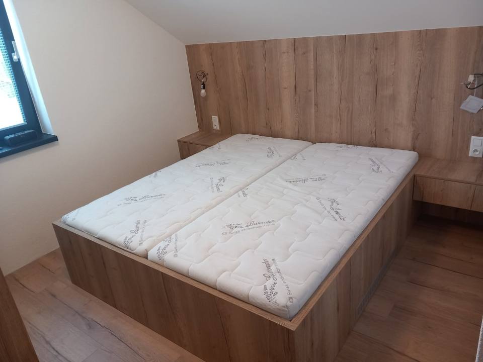 Doppelbett in Eichendekor mit hoher Wandverkleidung hinter dem Kopfteil