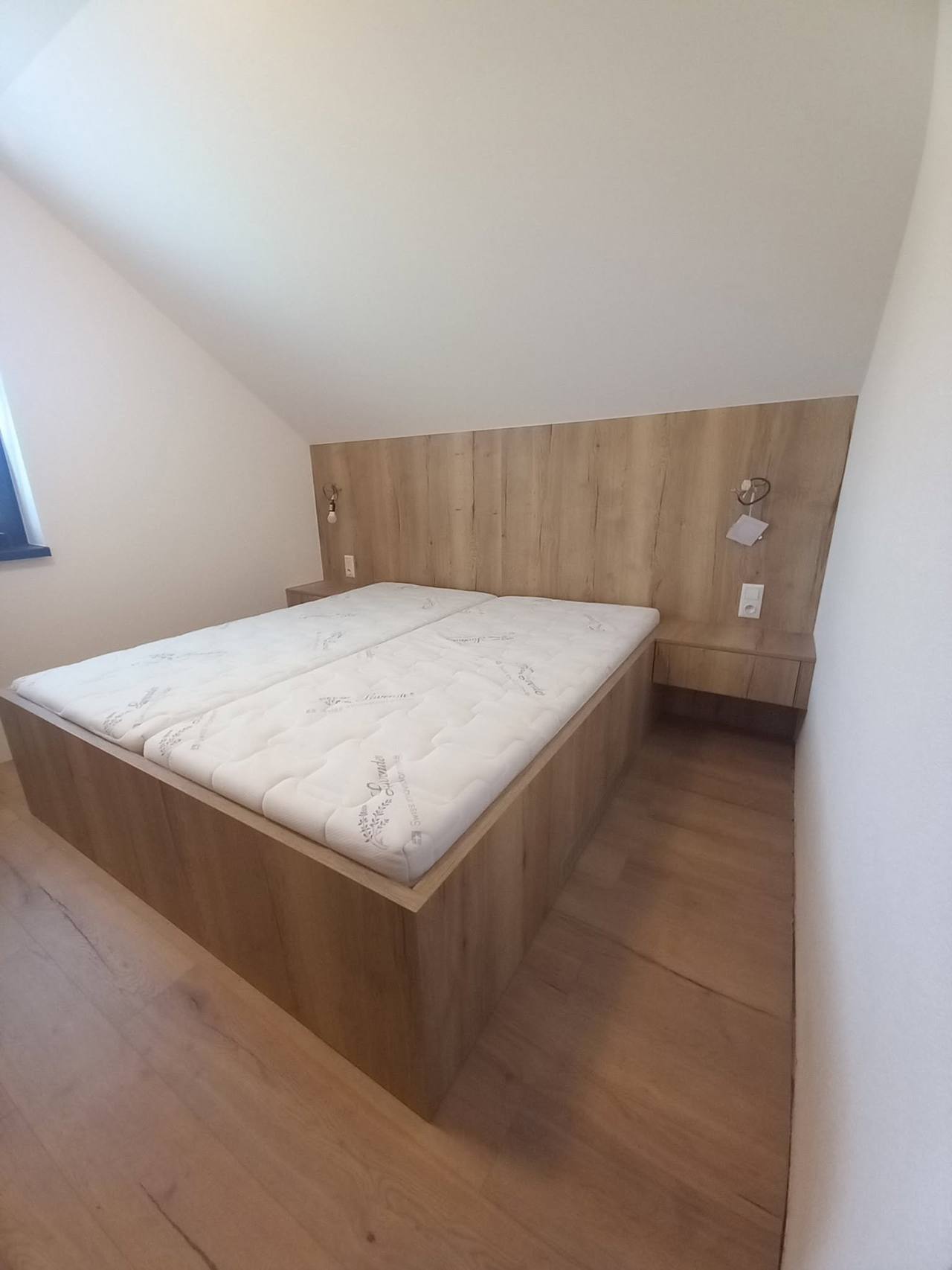 Doppelbett mit Verkleidung und Leuchten unter der Dachschräge