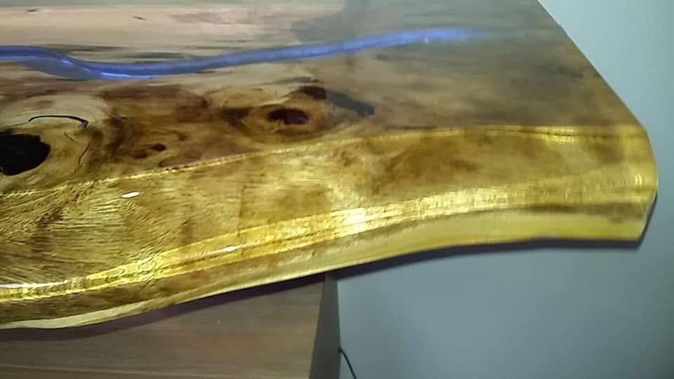 Baumkante des Bords mit blauem Epoxidharz-Fluss und Ästen im Detail