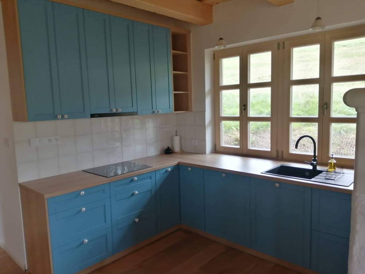 L-Küche mit blauen Hängekästen und offenen Regalen