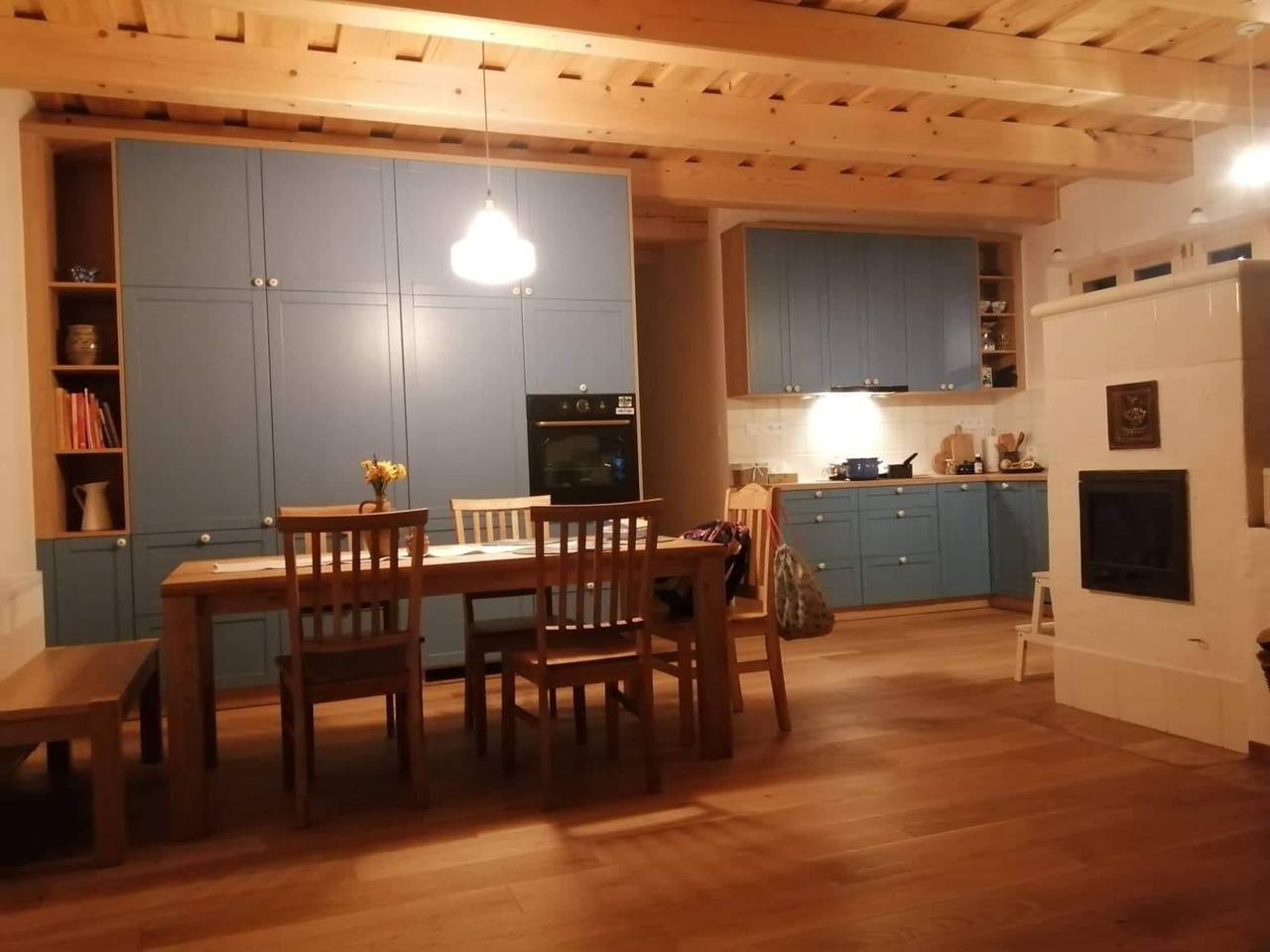 Modrá kuchyňa s jedálenským stolom pod dreveným stropom