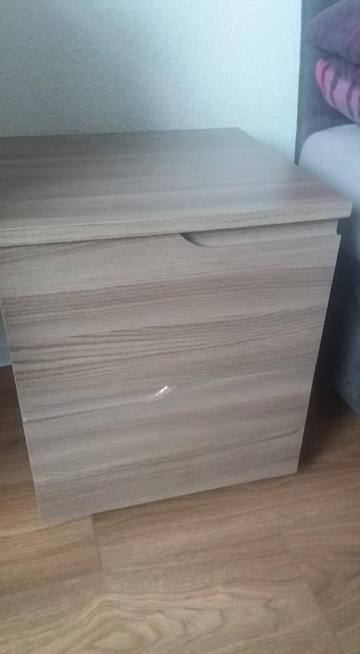 Nachtkästchen in graubraunem Holzdekor neben dem Polsterbett