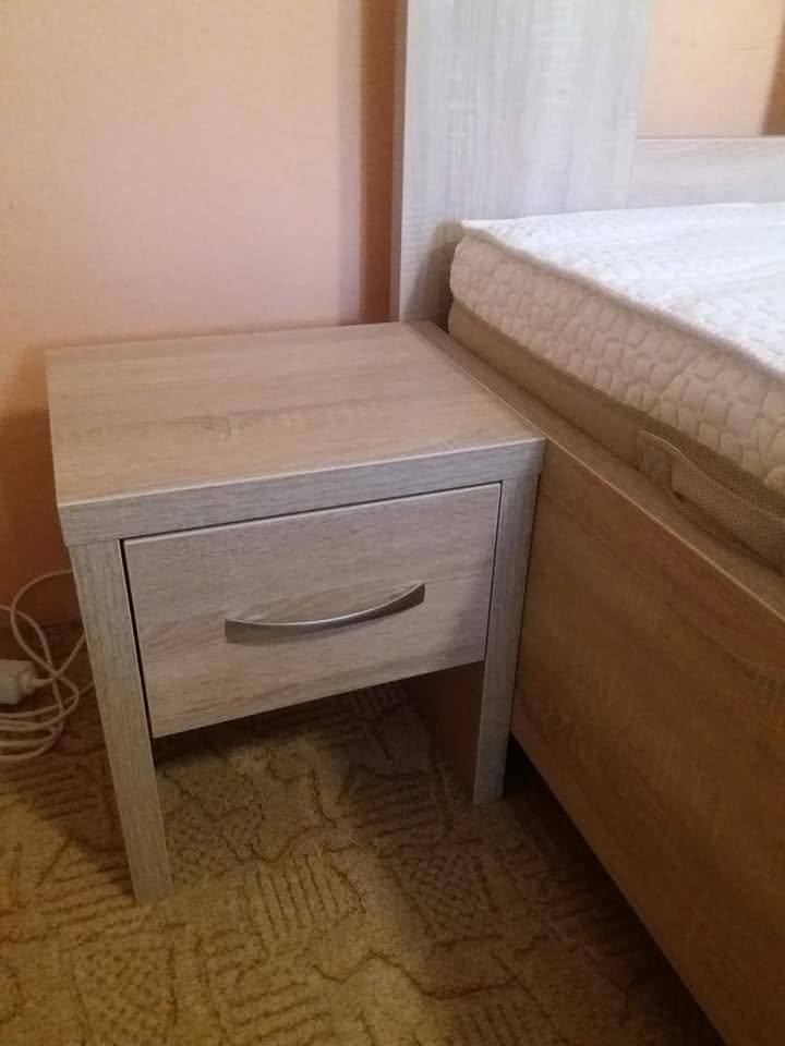 Nachtkästchen mit Lade in grauem Dekor neben dem Bett