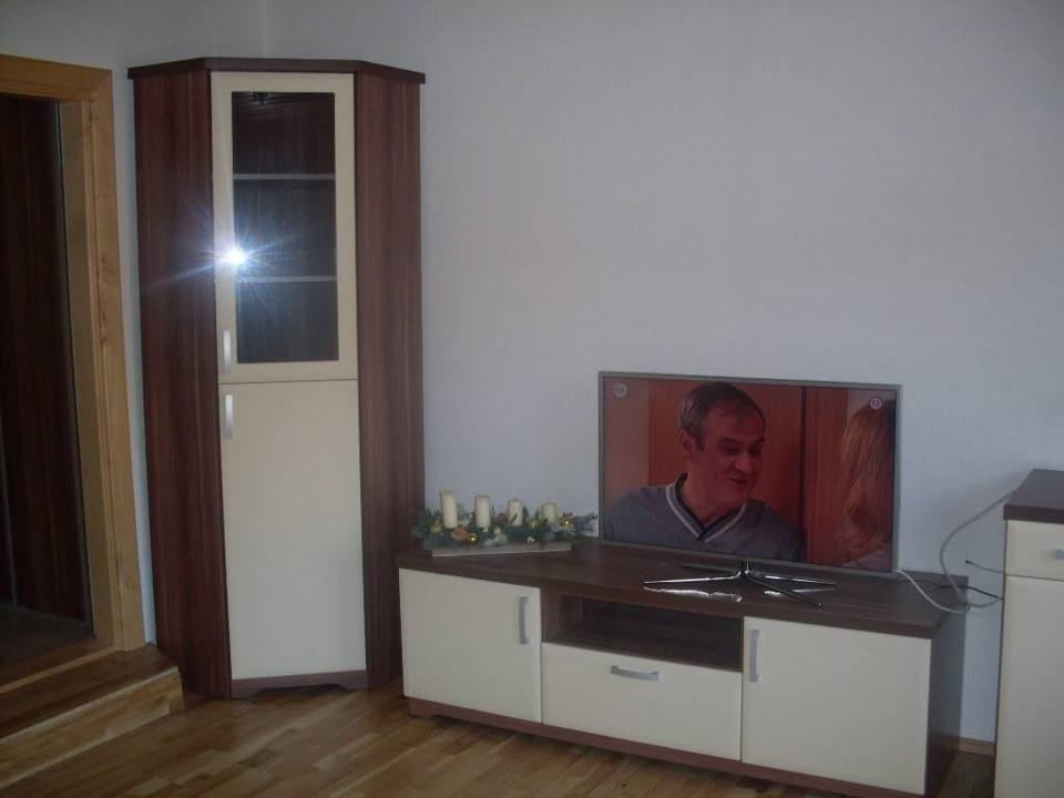 Eckvitrine in Nussoptik mit Beleuchtung und weißes TV-Lowboard