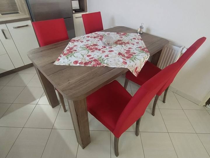 Esstisch mit Tischdecke und roten Polsterstühlen