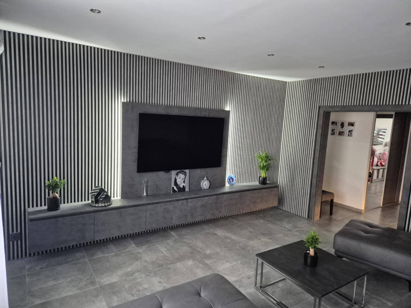Frontansicht der TV-Wand mit Lamellen und langem Hängeelement