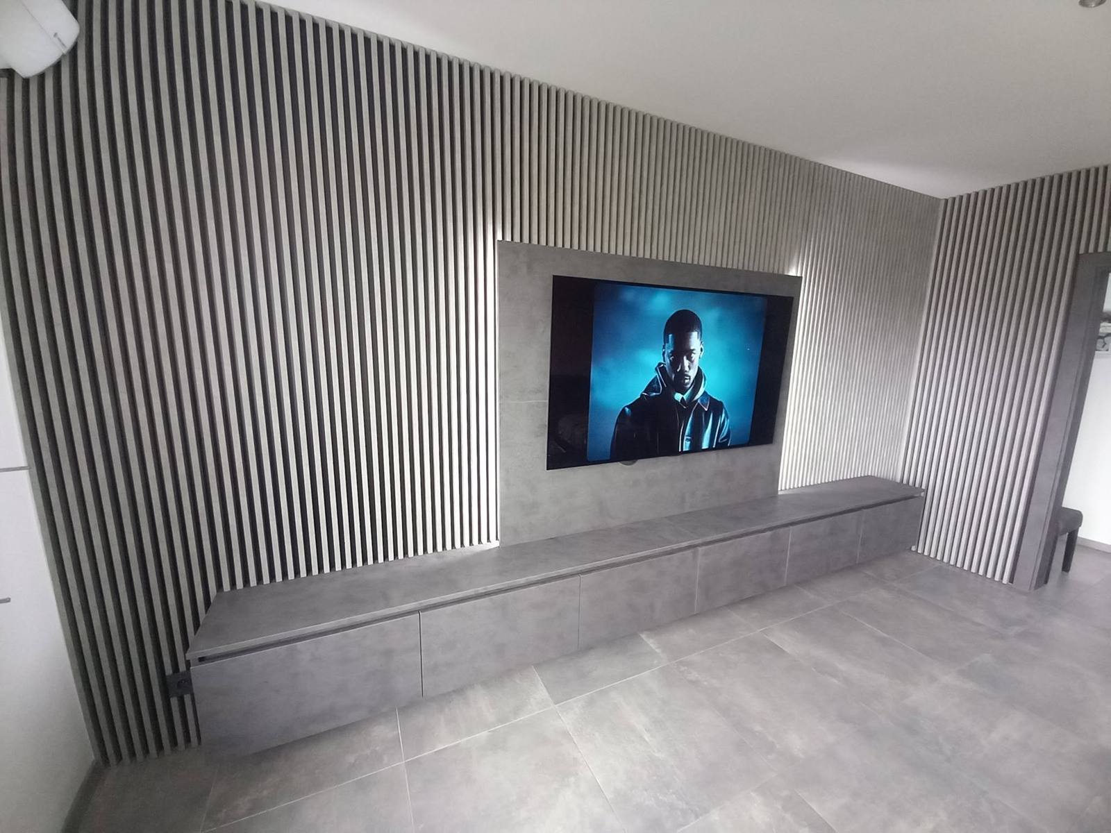 Graue Lamellenwand mit hinterleuchtetem TV-Paneel und Hängeelement