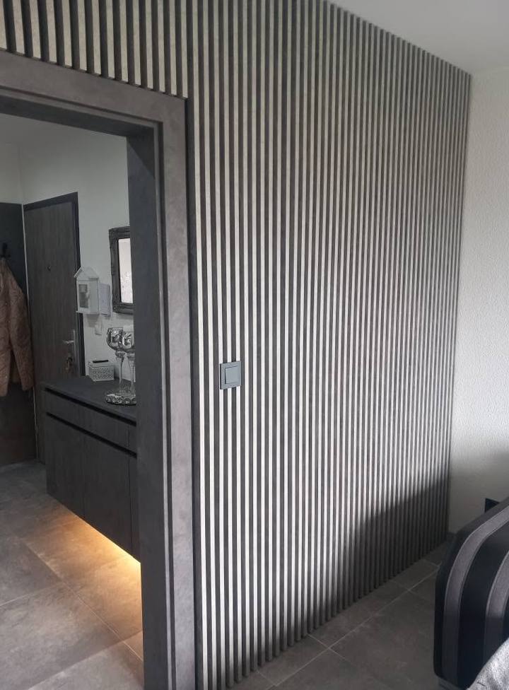 Durchgang mit dunklem Türstock in der Lamellenwand