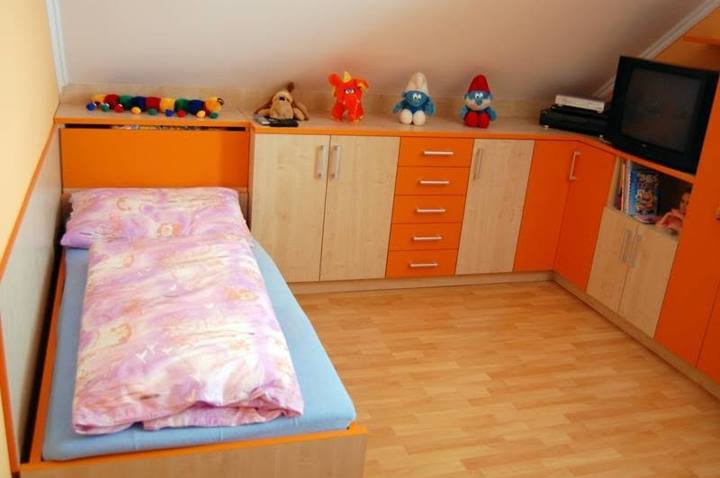 Dachgeschoss-Kinderzimmer mit Bett und orangefarbenem Eckkasten