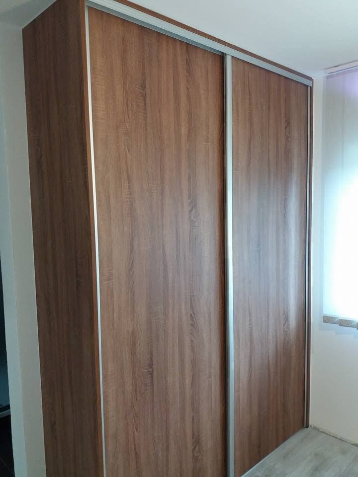 Nussbaum-Schwebetürenschrank bis zur Decke neben dem Fenster