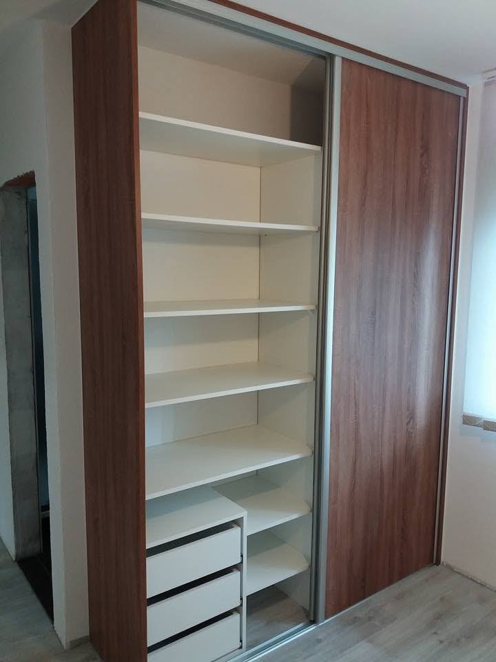 Geöffneter Kleiderkasten in Nussbaum-Dekor mit weißen Fachböden und Laden.
